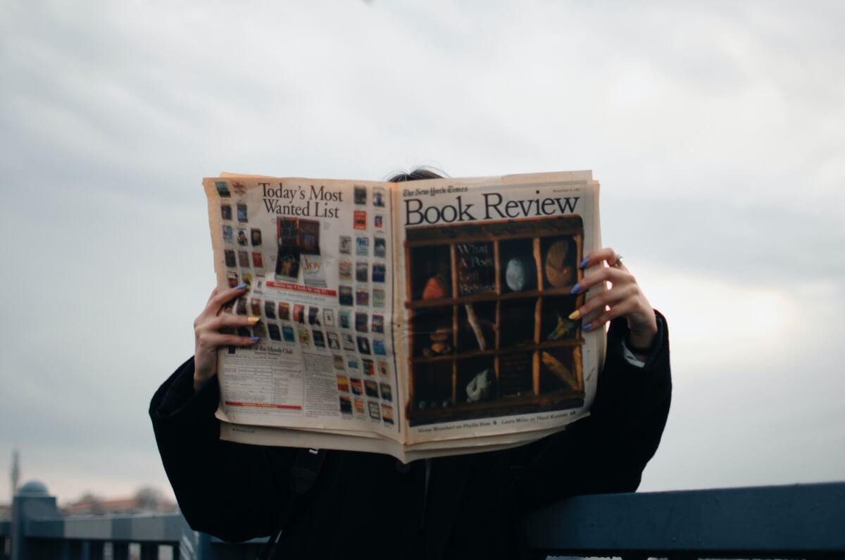 Buchrezension, Mann mit Zeitung, blauer Himmel