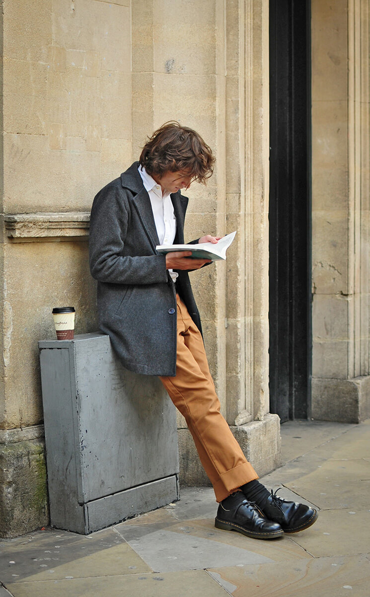 Lesen, Mann mit Buch lehnt an der Wand Selbsthilfe Ratgeber Poesie- und Bibliotherapie